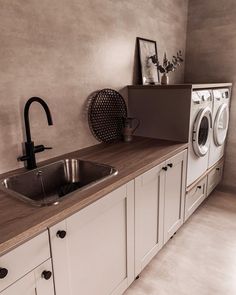 a washer and dryer in a small room with white cabinets, counter tops and drawers