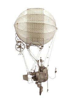 an old fashioned hot air balloon flying in the sky with wheels attached to it's side