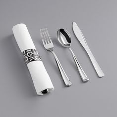 an assortment of utensils and silverware on a gray tablecloth with black designs