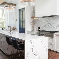 a kitchen with marble counter tops and an island in front of the stove top oven