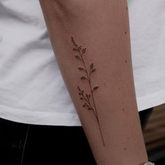 a woman's arm with a small flower tattoo on it