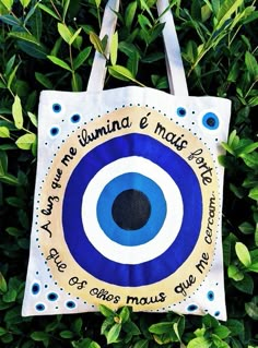 a blue and white bag with an evil eye on it hanging from a tree branch