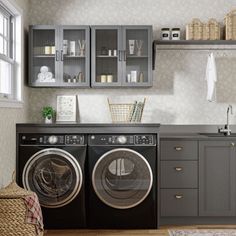 a washer and dryer in a small room with cabinets on the wall behind them