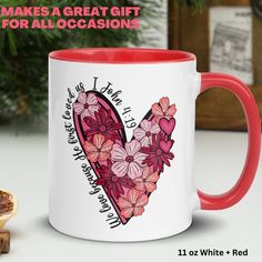 a red and white coffee mug sitting on top of a table next to a piece of bread