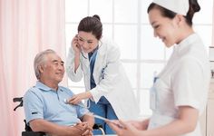 a nurse talking to an elderly man in a wheel chair while he talks on the phone