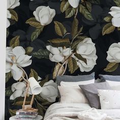 a bed sitting under a black wall with white flowers on it