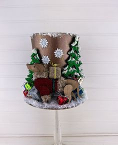 a small christmas decoration on top of a glass stand with snowflakes and trees