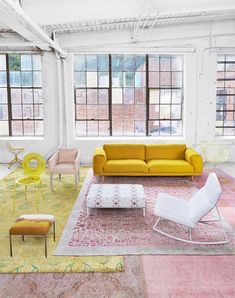 a living room filled with lots of furniture next to large windows and colorful rugs