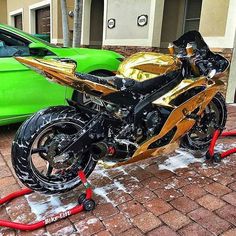 a gold and black motorcycle parked next to a green car