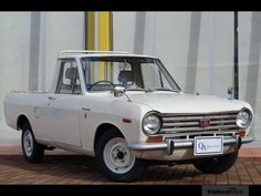 an old white car parked in front of a building