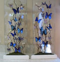 two glass vases with blue butterflies on them sitting on a counter in front of a mirror