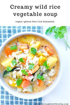 creamy wild rice vegetable soup in a white bowl on a blue and white checkered cloth