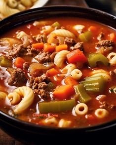 a bowl filled with pasta and meat soup next to crackers on the side,