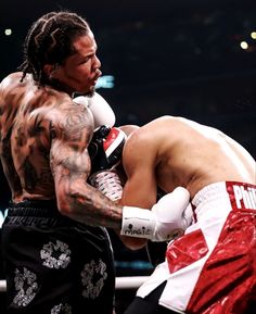 a man with tattoos on his arm standing next to another man wearing boxing gloves