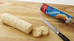 a can of crescents next to a peeled banana on a cutting board with a knife