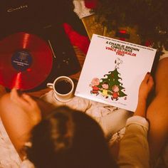 a person laying on the floor next to a record player and a christmas tree book