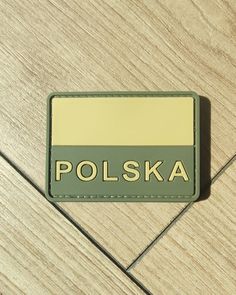 a patch with the word polska on it sitting on a tile floor in front of a wooden wall