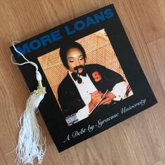 a book that is laying on top of a wooden table next to a tassel