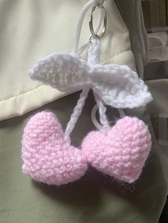 a crocheted pink and white baby booties hanging from a hook on a pillow