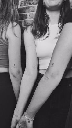 two women standing next to each other with tattoos on their arms and armbands