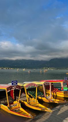 there are many boats parked on the dock by the water and mountains in the background