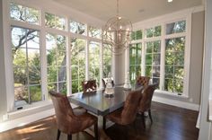 a dinning room table and chairs in front of large windows