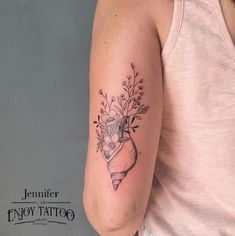 a woman with a tattoo on her arm holding a bouquet of flowers in her hand