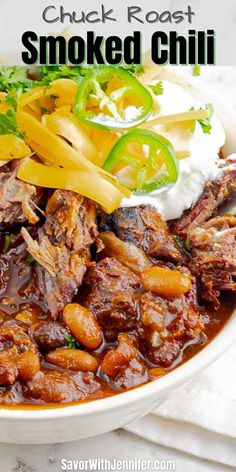 a white bowl filled with meat, beans and sour cream on top of a table