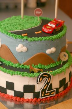 a birthday cake with cars on it sitting on a table