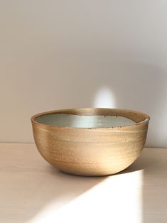 a wooden bowl sitting on top of a table next to a white wall and floor