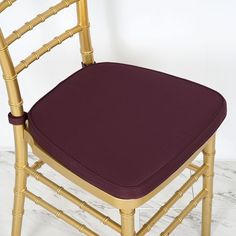 a close up of a chair with a purple seat pad and gold frame on it