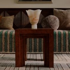 a vase sitting on top of a wooden table in front of a couch with pillows