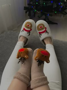 someone wearing slippers with reindeer faces on them sitting in front of a christmas tree