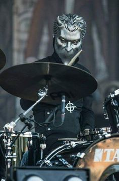 a man with makeup on his face playing the drums in front of a drum set