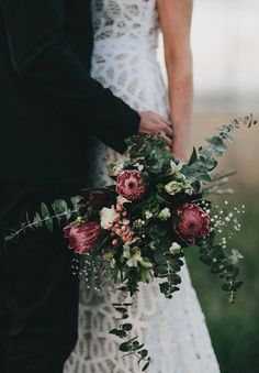 the bride and groom are holding hands with their bouquets in front of each other