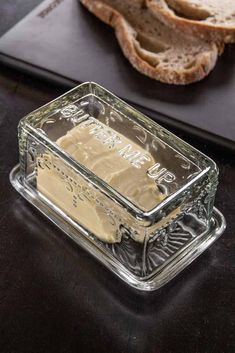 a loaf of bread sitting on top of a table next to a glass container filled with butter