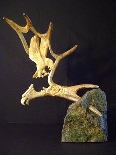 an animal sculpture made out of wood and rock on a black background with the image of two birds flying over it