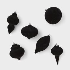 six black ornaments are arranged on a white surface