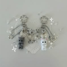 two key chains with charms attached to them on a doily covered table top,