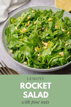 a salad with spinach and pine nuts in a white bowl next to a fork