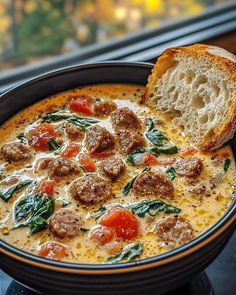 a bowl of soup with meatballs and spinach in it next to a slice of bread