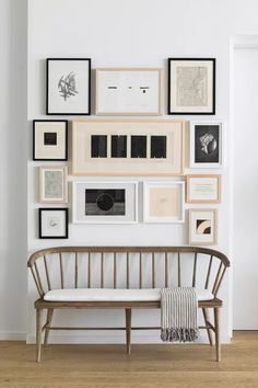 a white bench sitting in front of a wall filled with framed pictures on it's side