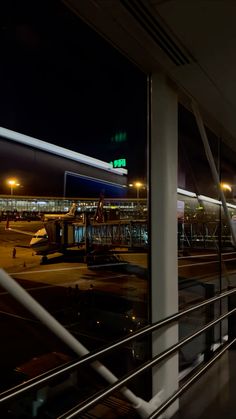 an airport terminal at night with planes parked on the tarmac and lights in the background