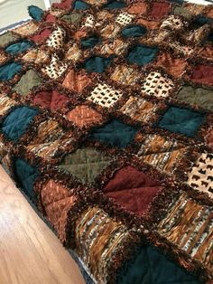 a bed covered in a multi colored quilt on top of a wooden floor next to a window