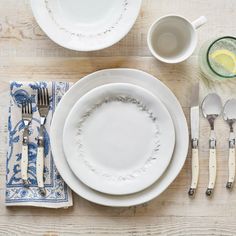 the table is set with white dishes and silverware