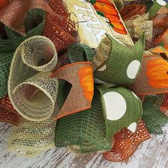 an orange and green mesh bow on top of a wooden table next to a bottle