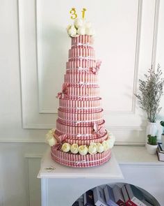 a large pink cake sitting on top of a white table next to a book shelf