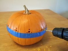 a pumpkin being carved with an electric drill