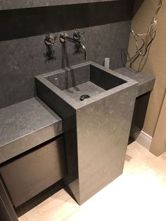 a bathroom sink sitting under a faucet next to a wall mounted soap dispenser