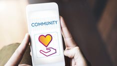 a person holding up a smart phone with the word community on it and a heart